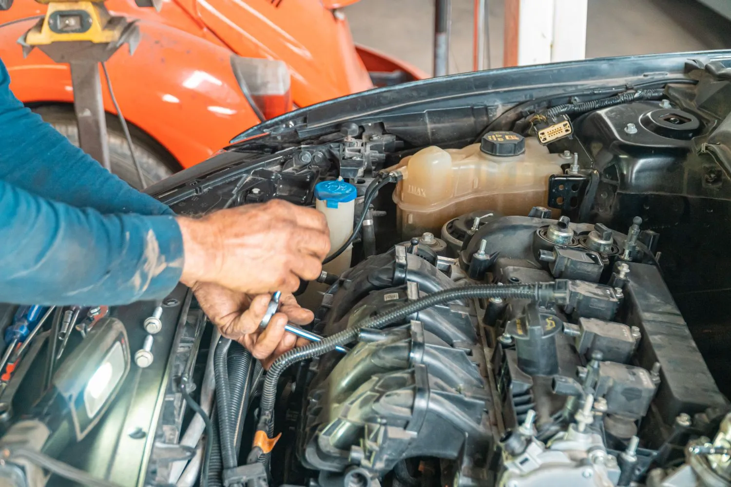 Mecanic lucrând în compartimentul motor al unei mașini
